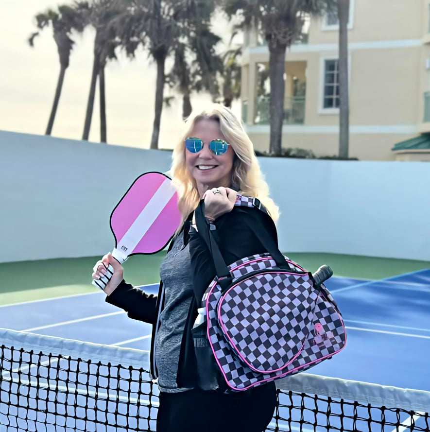 Stylish lady pickleball player on the court with pink stripe paddle and checkers sports bag and tote